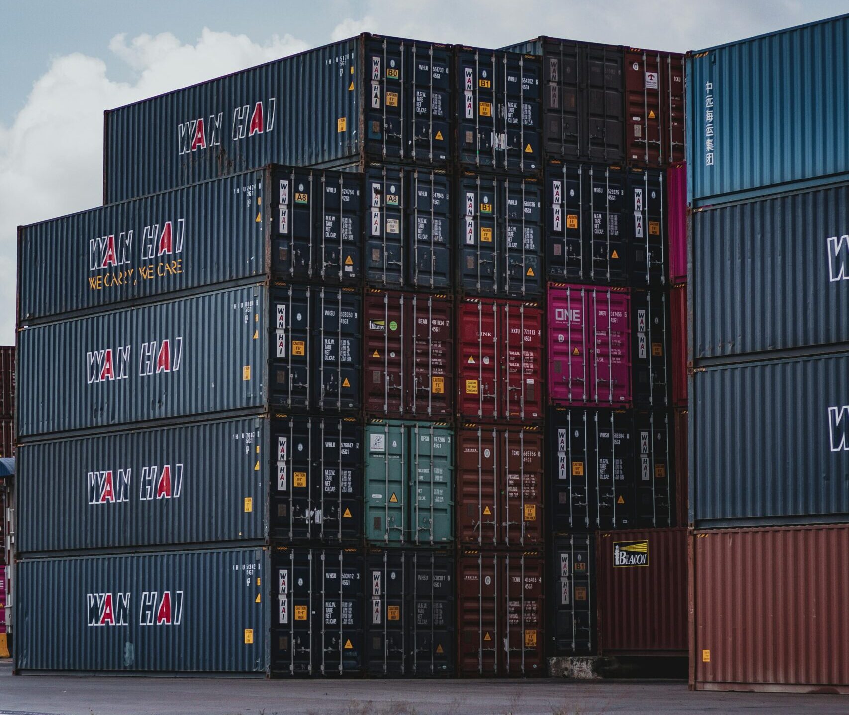 High vertical stack of cargo containers at a port, symbolizing global logistics.